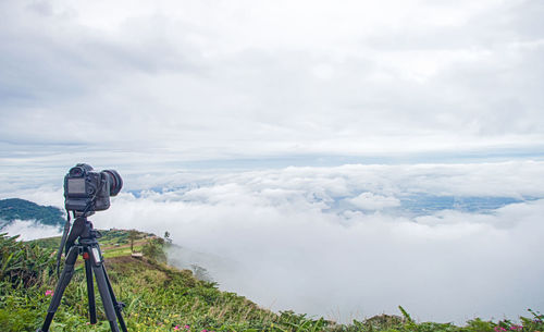 Close-up of camera on landscape against sky