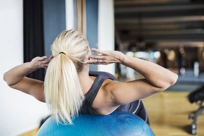 Young woman exercising on fitness ball at gym