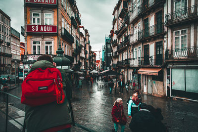 Rear view of people walking on street amidst buildings