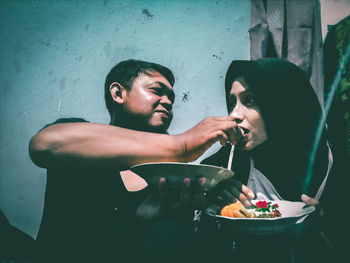 Young man having food against wall