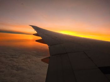 Airplane wing against sky during sunset