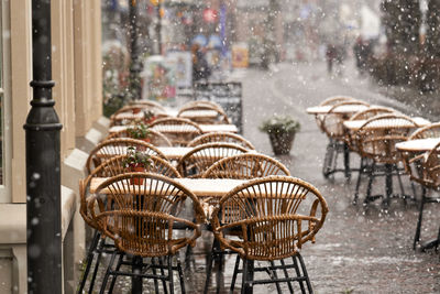 Empty chairs and tables at restaurant, outdoors with snow.