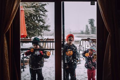 Children standing at glass window during halloween festival