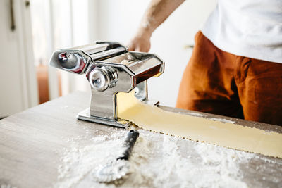 Midsection of male chef making food with machinery on table