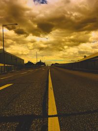 Empty road against cloudy sky during sunset