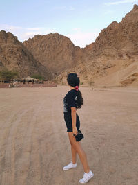 Full length of woman standing in front of mountain against sky