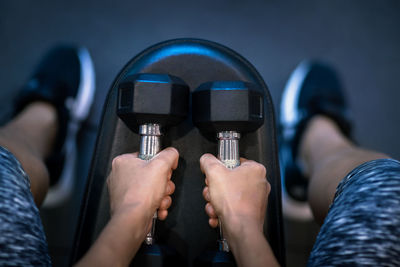 Midsection of woman holding dumbbell in gym