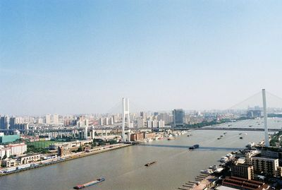 Cityscape by river against clear sky