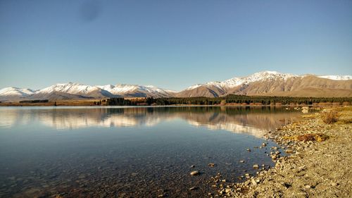 Scenic view of lake and mountains against clear blue sky