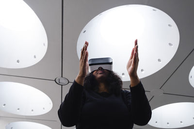 Woman gesturing while wearing virtual reality simulator