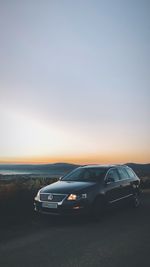 Cars on road against sky during sunset