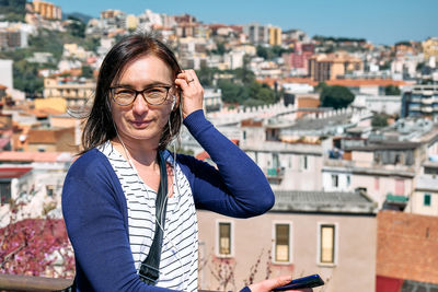 Happy smiling woman listening music, song or audio guide at mobile phone while enjoying a view