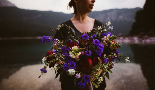 Close-up of woman standing by purple flowers against mountain