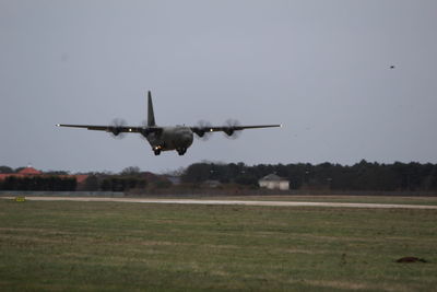 Airplane flying over field against sky