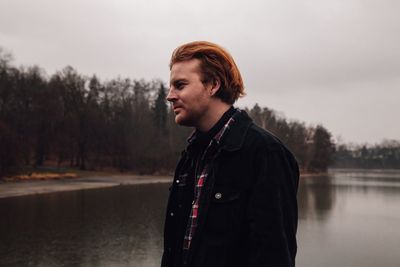 Man looking away while standing against sky