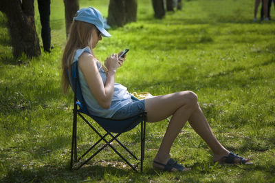 Rear view of man using mobile phone in grass