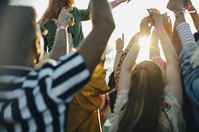 Rear view of crowd with arms raised enjoying in music festival