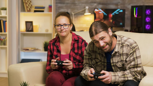Portrait of smiling friends using mobile phone while sitting at home
