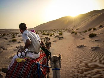 Rear view of man standing on desert against clear sky