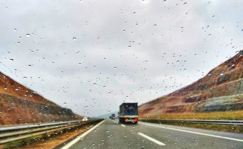 Cars on road seen through wet window during rainy season