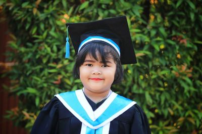 Portrait of smiling cute girl wearing graduation gown