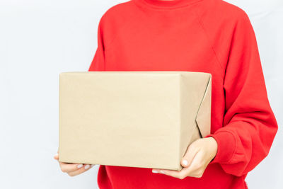 Midsection of woman holding red box against white background