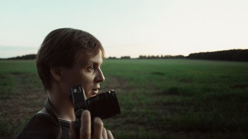 Portrait of man photographing camera on field