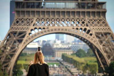 Rear view of woman photographing eiffel tower