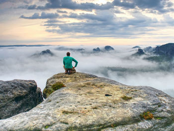 Professional photographer on knees at tripod look into fall land and thinking. hiker with tripod