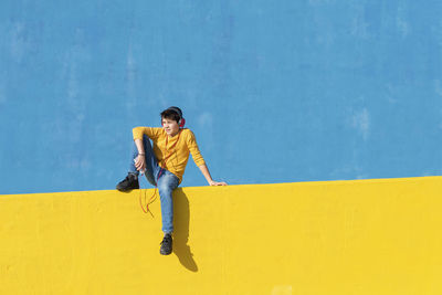 Full length of young man against yellow wall