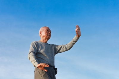 Low angle view of man standing against blue sky