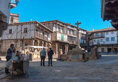 People on street against buildings in city