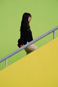 Side view of woman against yellow wall