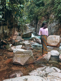 Rear view of woman walking on rocks in forest