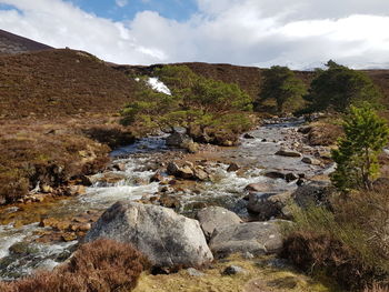 Scenic view of stream amidst rocks against sky