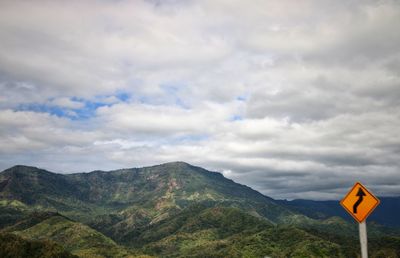 Road sign by mountains against sky