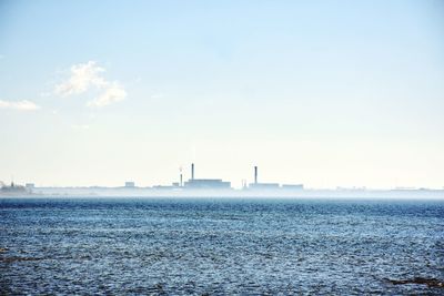 View of factory by sea against clear sky