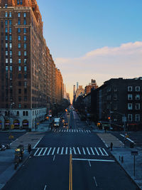 City street and buildings against sky during sunset