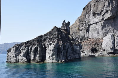 Rock formations by sea against clear sky