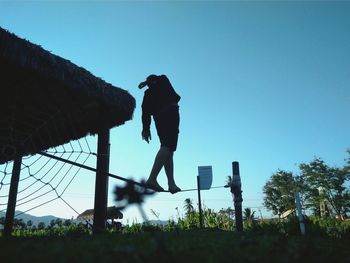 Low angle view of silhouette man jumping against clear sky