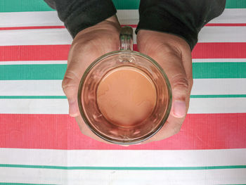 High angle view of hand holding drink on table