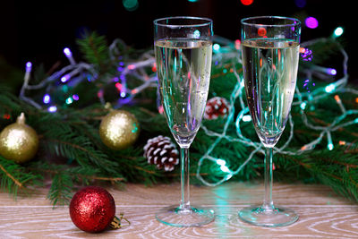 Close-up of champagne flutes by christmas decoration on table