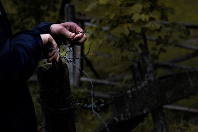 Midsection of person holding barbed wire