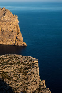 Rock formations by sea against blue sky