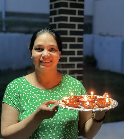 Portrait of young woman holding sparkler at home