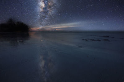 Scenic view of sea against star field in sky at night