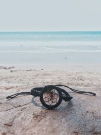 Close-up of sunglasses on beach against sky