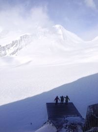 People standing on snow covered mountain by sea against sky