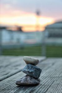 Stack of stones on pier by sea against sky during sunset