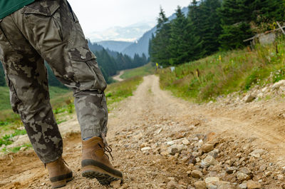 Low section of man standing on dirt road